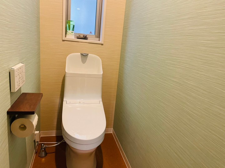 使っていないトイレの設備を撤去して広々とくつろげるトイレスペースに！微妙に異なる色糸を織りあわせたような質感のクロスでさらに落ち着く空間に！