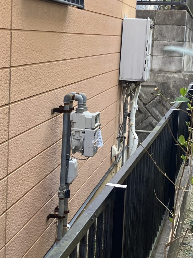 外壁に設置された旧型給湯器。配管まわりに経年劣化が見られ、交換時期を迎えていました。