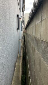 建物側面の狭小通路。高圧洗浄や塗装の際、隣地との距離が近く、養生と飛散防止に配慮が必要でした。